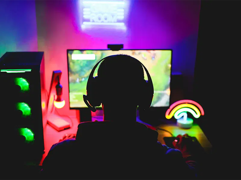 A gamer at a neon-lit setup, headphones on, mid-session